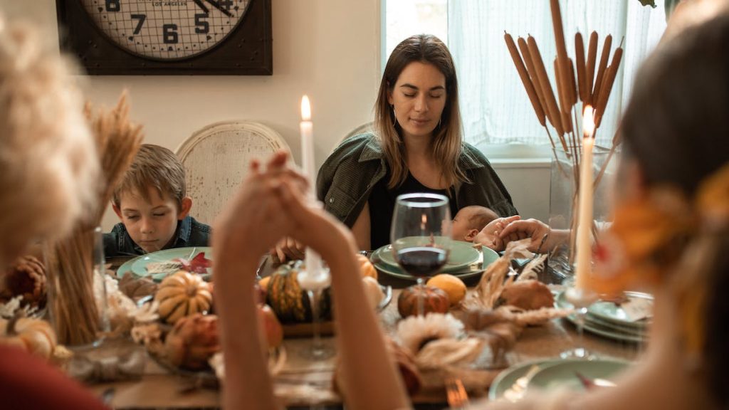 Una familia ora con gratitud alrededor de una mesa repleta