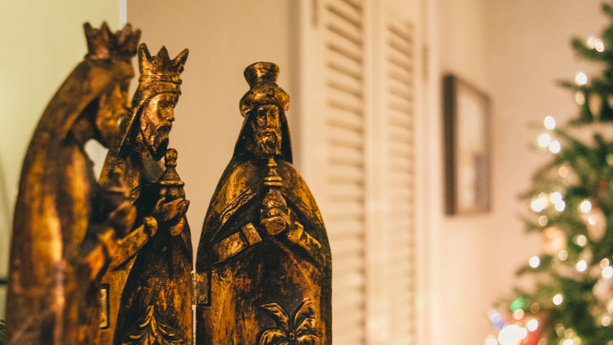 El significado de los regalos de los Reyes Magos: figuras doradas de los Reyes Magos en un salón, con un árbol de Navidad al fondo