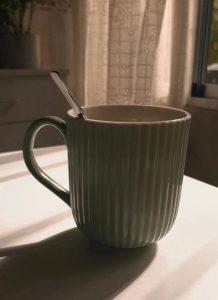 taza verde en una mesa con cortina blanca de fondo para ilustrar blog sobre la esperanza