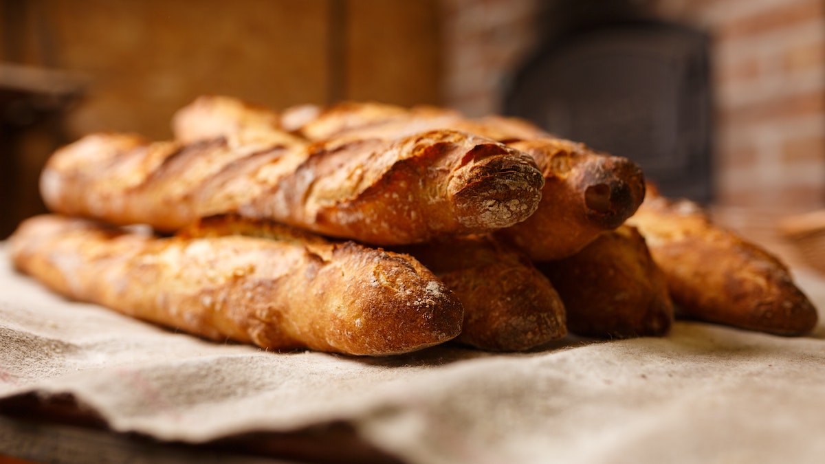 No solo de pan vive el hombre: 6 barras de pan recién horneadas descansan en un paño de cocina