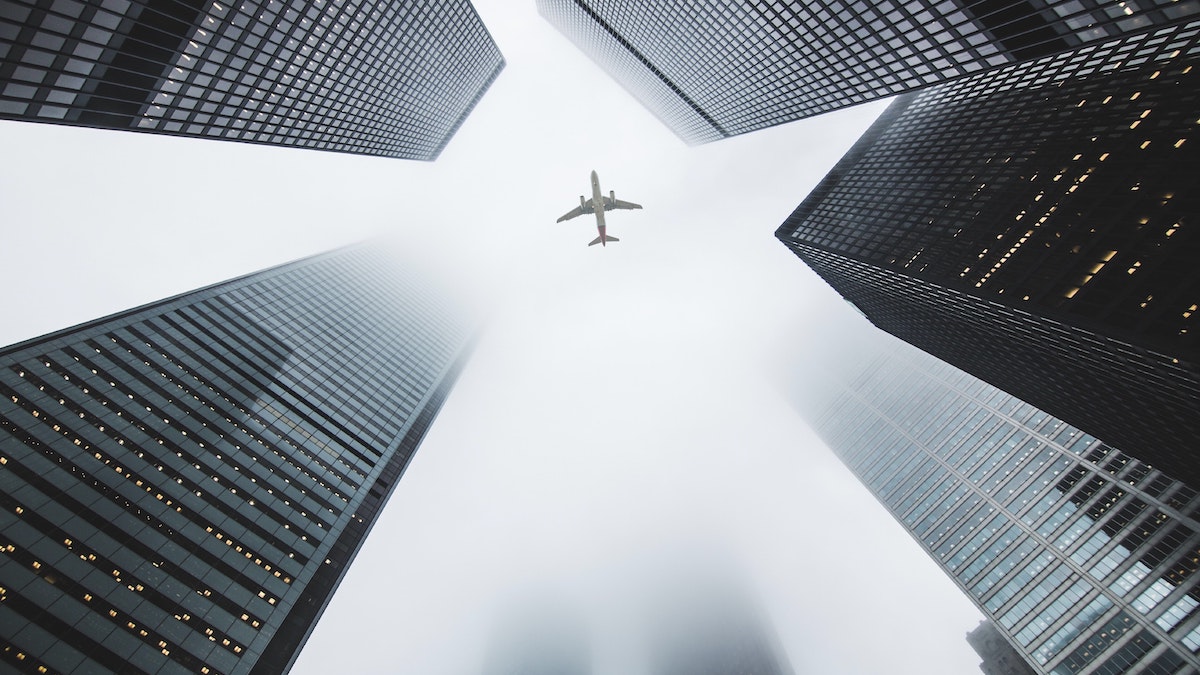 Tener fe: un avión cruza el cielo en medio de varios rascacielos