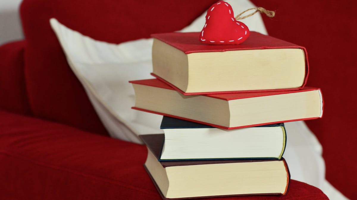 pila de libros con llavero corazón rojo en un sofá rojo para blog sobre libros recomendados cristianos en el día del amor y de la amistad